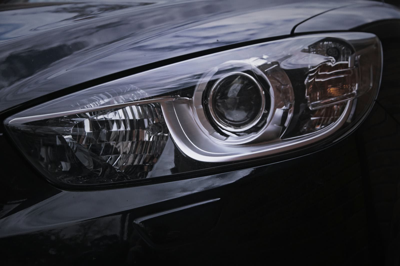 Close-up of a crystal-clear, restored headlight lens on a black car